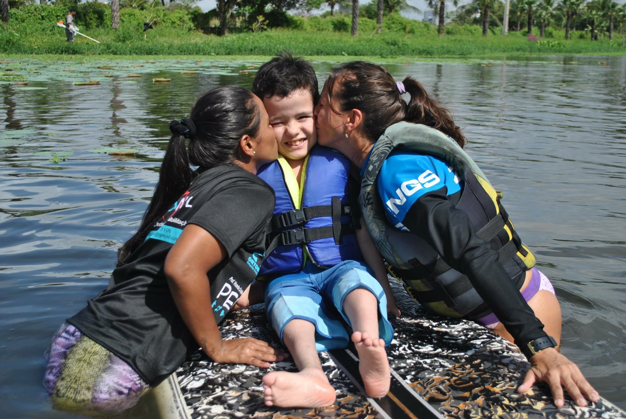 Grupo de participantes e voluntários em atividade aquática com canoa havaiana